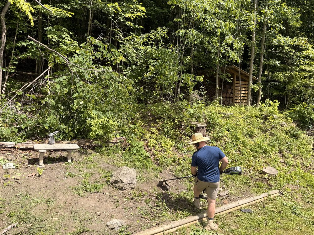A Magnolia Gardens pro clearing an overgrown bed with a string trimmer before mulching